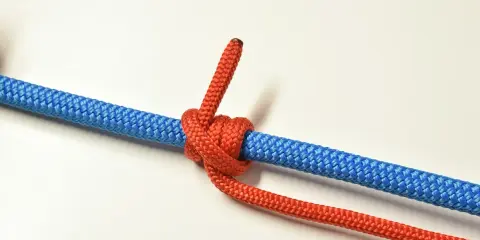 Un nœud de bosse rouge est solidement attaché à une corde bleue, prêt pour une aventure.