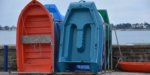 Plusieurs petites embarcations colorées, dont une annexe orange, sont rangées sur un quai.
