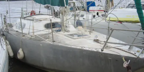 Voilier gris amarré, prêt pour une brise de mer 31. Voiles vertes et bleues, cordages et bouées.
