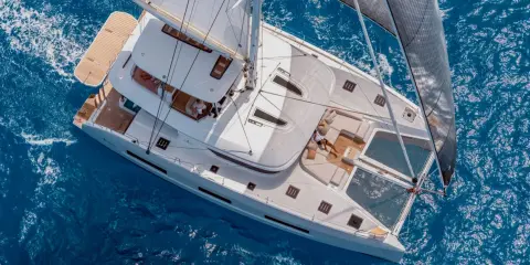 Vue aérienne d'un catamaran blanc naviguant sur une mer bleue. Ce bateau est le meilleur catamaran hauturier, idéal pour explorer les océans.