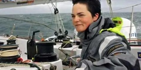 La navigatrice Ellen MacArthur, compagnon de bord sur un voilier, ajuste une voile.