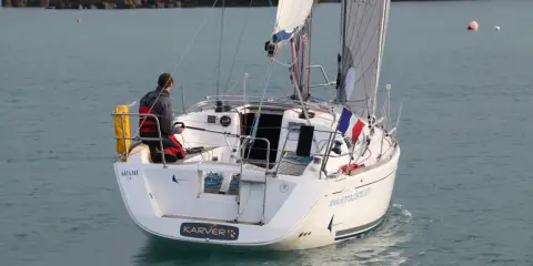 Un voilier Dufour 325 Grand Large navigue, un homme à la barre. Avis de navigation en mer.