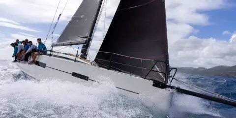 Équipage sur un voilier blanc, gery trentesaux, naviguant sur une mer agitée sous un ciel nuageux.