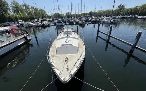 Un voilier blanc, type Westerly Centaur, est amarré dans un port. D'autres bateaux sont visibles au loin.