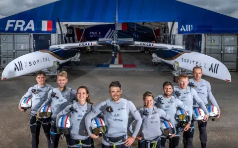 L'équipe française du SailGP France pose fièrement devant son catamaran, prête à conquérir les océans.