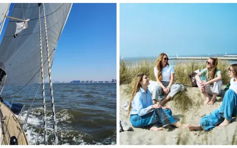 Un voilier prend le large, ses voiles gonflées par le vent. Sur la plage, des amies profitent du soleil, un moment de détente avant d'embarquer pour une nouvelle aventure.