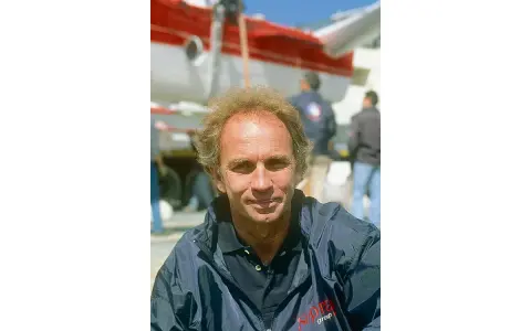 Jean-Claude Parisis, navigateur, souriant devant un avion rouge et blanc.