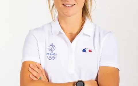 Manon Audinet, athlète française, porte un polo blanc avec les anneaux olympiques et le coq gaulois.