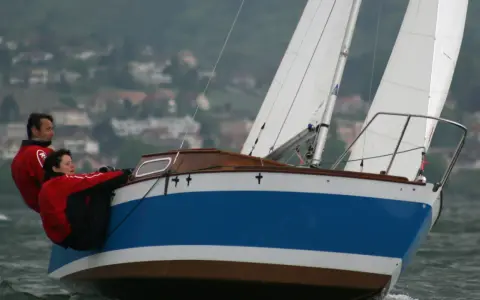 Couple en action sur un voilier transportable hauturier, profitant d'une navigation par temps frais.