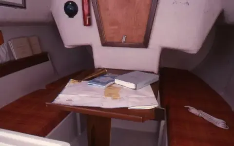 Vue du premier 22 intérieur d'un voilier, avec une carte marine, des livres et un compas.