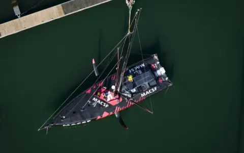 Le voilier MACSF, piloté par Corentin Horeau, est hissé hors de l'eau par une grue.