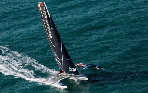 Le trimaran Maserati, skippé par Giovanni Soldini, fend les vagues bleues, laissant une traînée d'écume.