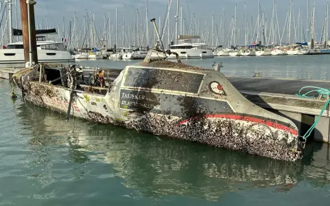 Un bateau coulé, couvert de coquillages, est amarré dans un port. Le nom "Talisker Whisky Atlantic Challenge" est visible.
