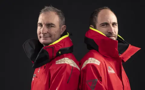 Morgan Lagravière et son coéquipier, deux marins en veste rouge, prêts pour l'aventure en mer.