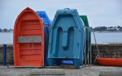 Plusieurs petites barques colorées sont rangées sur le quai, prêtes à être utilisées pour rejoindre son bateau.