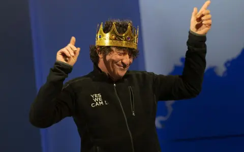 Jean Le Cam, le roi des mers, porte une couronne dorée et une veste noire avec l'inscription "YES WE CAM L".