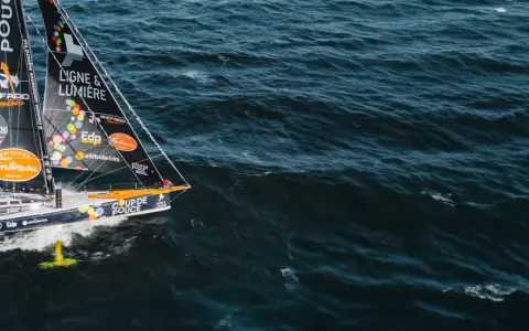 Voilier "Coup de Pouce" naviguant sur une mer agitée, avec le nom "Manuel Cousin" visible sur la voile.