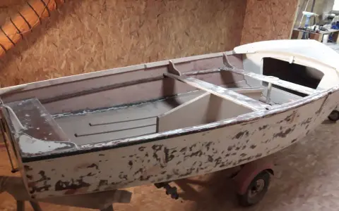 Un dériveur Caravelle polyester en cours de restauration, sur sa remorque. La coque est décapée, prête pour une nouvelle peinture.
