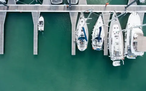 Vue aérienne d'un port avec plusieurs voiliers amarrés. Le coût de l'assurance bateau dépend de nombreux facteurs.