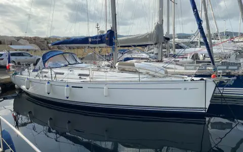 Un voilier Dufour 385 Grand Large blanc, amarré dans un port, reflète son élégance sur l'eau calme.