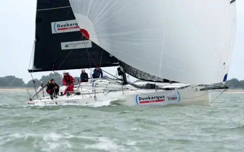 Un voilier "Dunkerque Voile" navigue avec un équipage concentré. Eliott Coville, peut-être à bord, profite de la course.