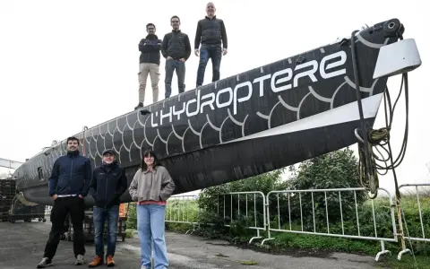 L'équipe pose fièrement devant l'hydroptère 2.0, un navire futuriste prêt à fendre les flots.