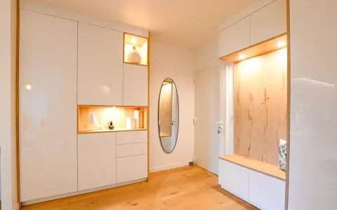 Ambiance chaleureuse dans cet intérieur de Kelt 550, avec des rangements blancs laqués et des niches en bois illuminées. Un miroir ovale ajoute une touche d'élégance.