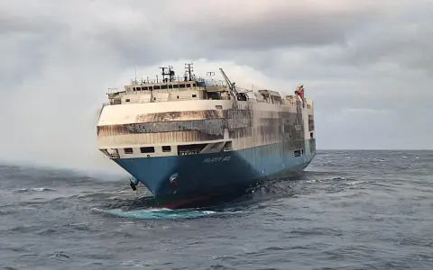 Le cargo Felicity Ace, en feu, dérive sur une mer agitée. De la fumée s'échappe de ses ponts supérieurs.