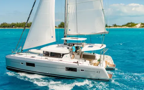 Catamaran Lagoon 42 naviguant sur des eaux turquoise. La fiche technique de ce voilier de luxe promet des croisières inoubliables.