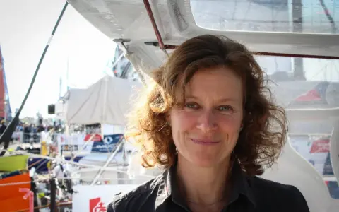 Isabelle Joschke, souriante, sur un bateau, prête pour une nouvelle aventure maritime.