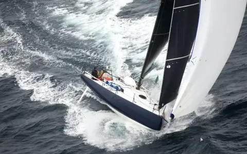 Un voilier de course fend les vagues, ses voiles noires et blanches gonflées par le vent. On dirait qu'il nous montre comment naissent les bateaux, prêts à conquérir l'océan.