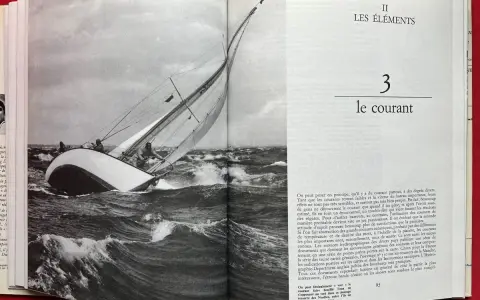 Un voilier navigue dans une mer agitée, ses voiles gonflées par le vent. Alain Gliksman, passionné de voile, admire cette scène.