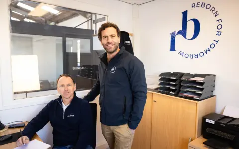 Dimitri Caudrelier et son collègue dans leur bureau, avec le logo "Reborn for Tomorrow" au mur.