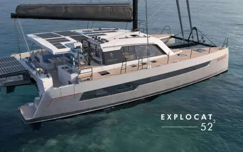 Un catamaran de luxe, un **deriveur integral** moderne, navigue sur des eaux bleues claires. Panneaux solaires sur le toit, design épuré.