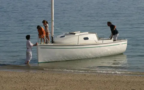 Une famille prépare son voilier, icône 6, pour une sortie en mer. Les enfants montent à bord, impatients de naviguer.