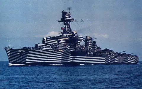 Un navire de guerre à l'impressionnant camouflage zébré, conçu pour tromper l'ennemi. Ce bateau militaire arbore un motif audacieux.