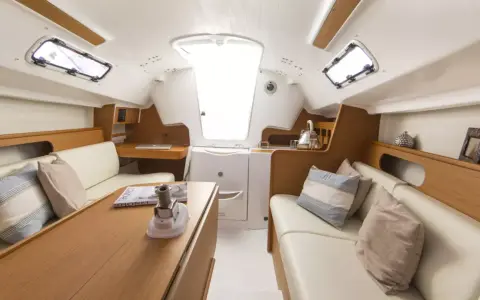 L'intérieur d'un voilier moderne, avec des banquettes en cuir, une table en bois et des hublots. Le premier 25 interieur est lumineux et spacieux.