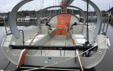 Le voilier "L'Abri Cotier" SB, un modèle kaidoz 31, est amarré dans un port. Son design moderne avec une arche distinctive est visible.