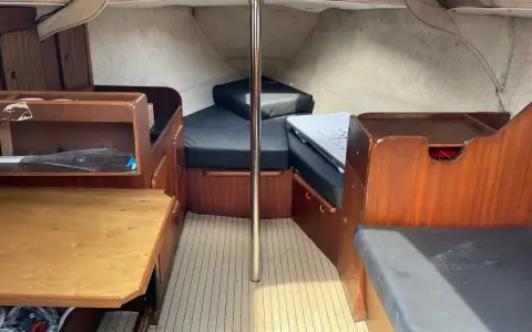 L'intérieur du Jeanneau Brio offre un espace de vie confortable avec des banquettes en tissu noir, une table en bois et des boiseries chaleureuses.