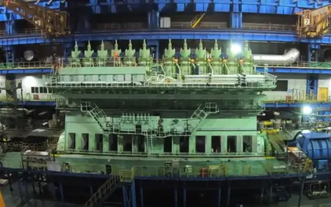 Un immense moteur vert, prêt à propulser un porte-conteneurs, se dresse dans un atelier de construction navale.