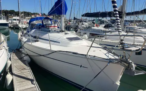 Bavaria 32, un voilier blanc avec une voile bleue, amarré dans un port. Avis sur ce modèle de bateau.