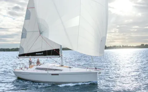Voilier Dehler 34 naviguant par temps calme. Les voiles blanches sont gonflées, deux personnes sont à la barre. Fiche technique du bateau.