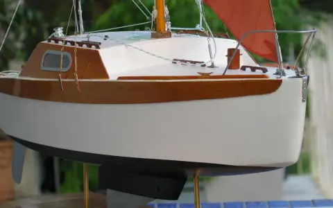 Modèle de voilier corsaire, coque blanche et bois verni, voile orange. Fiche technique détaillée.