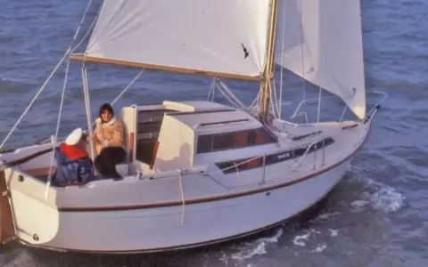 Un voilier Evasion 22 navigue sur une mer agitée, deux personnes à bord profitent de la brise.