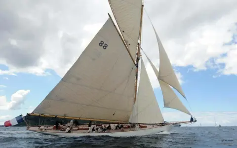 Le voilier "Moonbeam 4" navigue sur une mer agitée, ses voiles blanches gonflées par le vent.