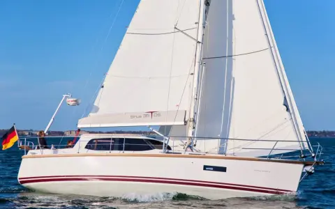 Voilier blanc Sirius 35 DS naviguant sur une mer bleue, avec le drapeau allemand à l'avant.