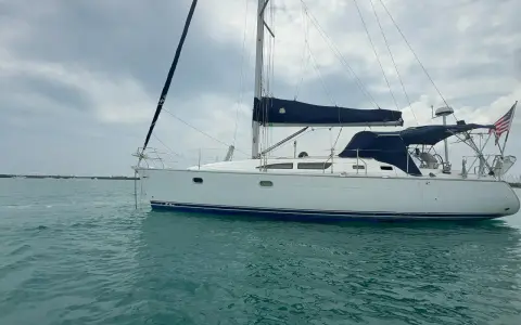 Voilier blanc à l'ancre, voiles bleues repliées. Un avis sur le Sun Odyssey 37, prêt pour l'aventure.