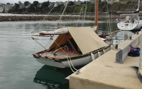Un cotre de Carantec, "Le Vieux Gui", est amarré au port. Une autre voile blanche est visible à côté.