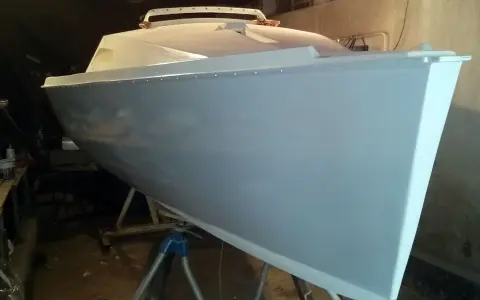 Le bateau Neptune 550, prêt pour sa nouvelle peinture, repose sur des supports dans un atelier.