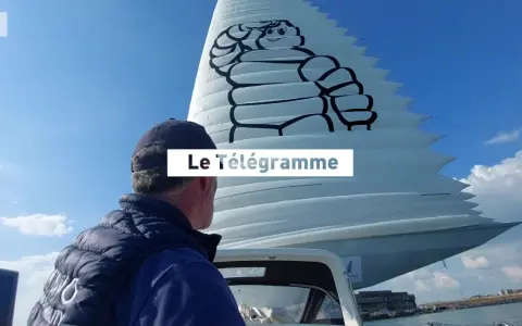 Un homme regarde une voile géante ornée du logo Michelin. Le Télégramme est affiché sur la voile.